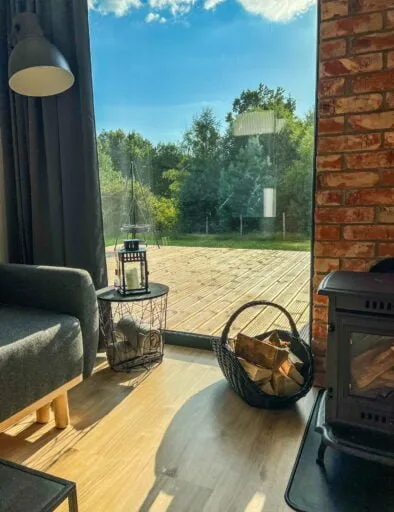 Widok z salonu na drewniany taras i las